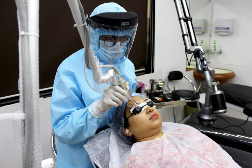 A medical practitioner performs laser treatment on a woman for skin care.
